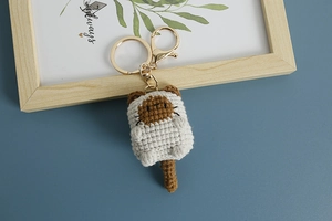 Close-up of a handmade crochet cat keychain with golden metal ring and hook detail