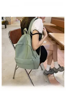 Detailed view of casual large capacity green nylon backpack in a cafe setting