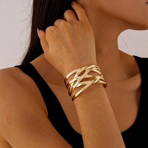 Close-up of golden multilayer crossover cuff bracelet with a polished geometric texture