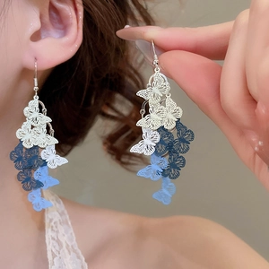 Detail view of painted hollow butterfly earrings with blue gradient fringe design