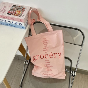 Sac fourre-tout en toile rose avec texte floral rouge dans un décor de style de vie