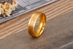 Dettaglio macro di un anello in acciaio spazzolato dorato con zircone su legno