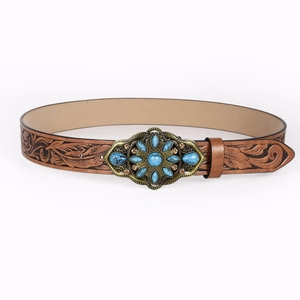 Close-up of brown leather belt with floral embossing and turquoise gemstone buckle
