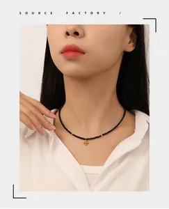 Close-up of black beaded choker necklace with golden cross flower pendant on model