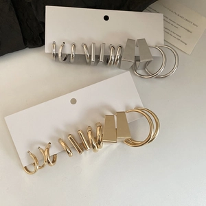 Close-up of geometric C-shaped hoop earrings set in polished gold and silver finishes