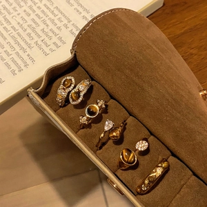 Dettaglio del set di anelli vintage placcati oro con occhio di tigre su camoscio marrone