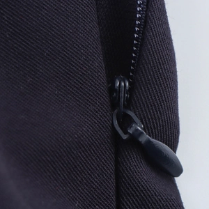 Detail of the hidden zipper on a black sleeveless preppy style pleated mini dress