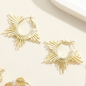 Detailed macro view of golden sunburst hoop earrings with radiant geometric texture