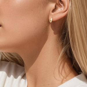 Macro detail of 18K gold teardrop stud earrings worn by model with metallic shine