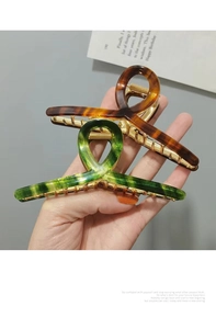 Close-up of large acetate claw clips in amber and gradient green with metal springs