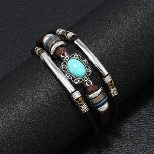 Handmade layered brown leather bracelet with turquoise pendant and steel tubes on black stand