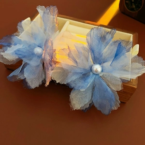 Close-up of blue gradient mesh flower hair clips with pearls on a wooden box