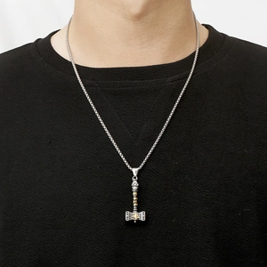 Detail of silver Mjolnir pendant with gold accents and Valknut symbols on woven chain