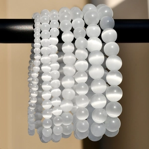 White opal stone beaded bracelets in multiple sizes with cat-eye effect on black display