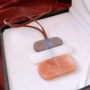 Macro view of acrylic irregular pendants in gray, white, and pink marble texture