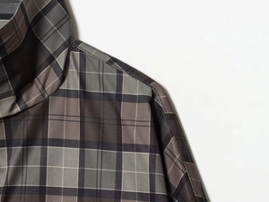 Close-up of the woven texture and stitching on a classic grey and brown plaid coat