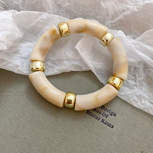 Close-up of geometric cream marble acrylic tube bracelet with gold metal spacers