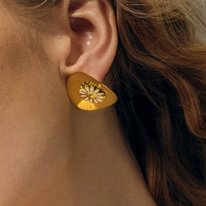 Close-up of 18k gold daisy stud earring with white enamel and 925 silver hallmark