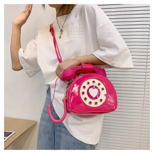 Detail of creative phone-shaped crossbody bag in pink patent leather with heart dial