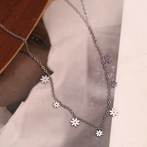 Detailed close-up of multiple silver daisy flower charms on a minimalist necklace