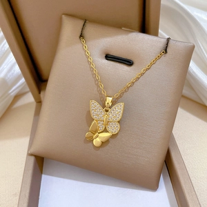 Macro detail of a gold titanium necklace with sparkling zircon double butterfly pendants