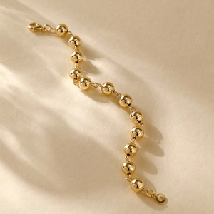 Detailed macro shot of 14K gold plated bead bracelet with secure lobster clasp finish