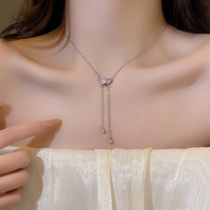 Detail of silver double heart necklace with light blue zircons and long tassel chains