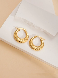 Detailed view of golden hoop earrings with organic hammered texture and shiny finish