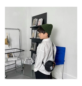 Détail d'un petit sac rond noir en nylon pour enfant avec chaîne et bonnet en tricot