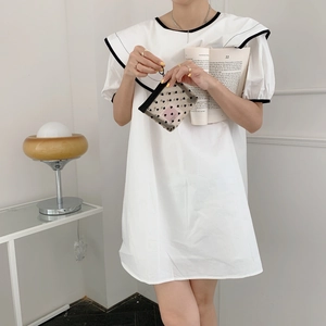 Detail of a black mesh heart pattern cosmetic bag held by a model in a minimalist setting