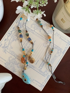 Bohemian beaded necklace featuring turquoise droplet pendant and gold metal accents