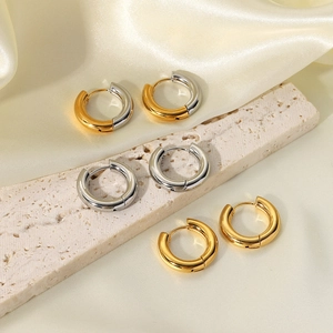 Three pairs of chunky hoop earrings in gold, silver, and two-tone finishes on stone