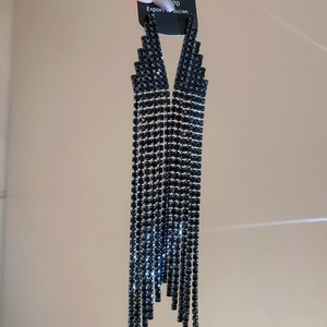 Macro detail of long black tassel earrings featuring rows of shimmering rhinestones