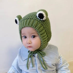 Detail of baby knitted frog hat featuring large 3D eyes and soft green crochet texture