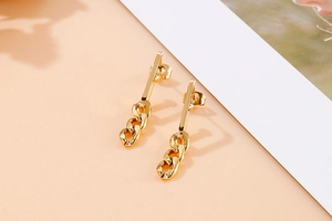 Detail of gold titanium steel earrings with a polished Cuban link chain drop design