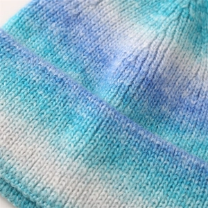 Macro shot of blue and white tie-dye gradient knit texture on a winter beanie hat