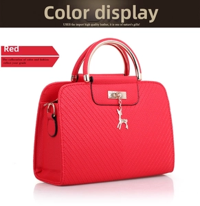 Detail view of red embossed leather satchel with metal handle and silver deer charm