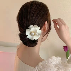 Detailansicht der mattweißen Blumen-Haarklammer mit Perle am Hinterkopf des Models