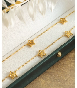 Macro view of gold plated star pendants with inlaid crystals on a titanium steel chain