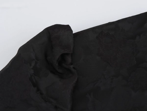 Detailaufnahme der schwarzen Blumenprägung auf dem eleganten Langarmkleid