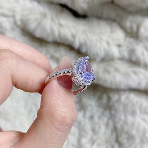 Detailed macro view of pear cut lavender gemstone ring with sparkling halo and pave band