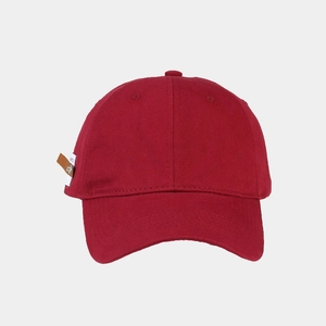 Detail view of burgundy cotton baseball cap with retro white fabric label and metal fastener