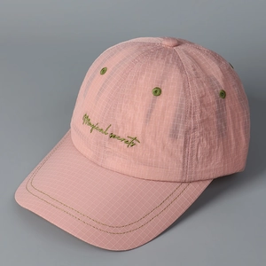 Close-up of pink plaid baseball cap featuring green Magical secrets cursive embroidery