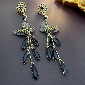 Macro detail of luxurious butterfly tassel earrings with black teardrop crystals
