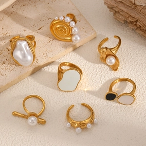 Baroque pearl stainless steel rings with gold finish and enamel on stone background