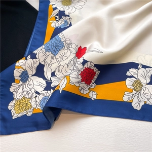 Detailed close-up of vibrant floral print scarf with fine rolled edge stitching