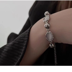 Detailed close-up of a silver chain bracelet with moonstone accents on a model's wrist