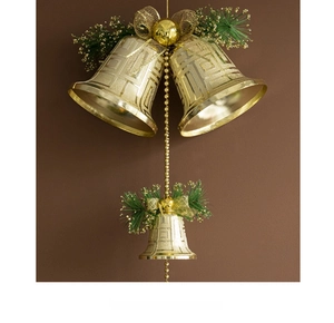 Detail of gold Christmas bells with pine needles and glitter bow on warm background
