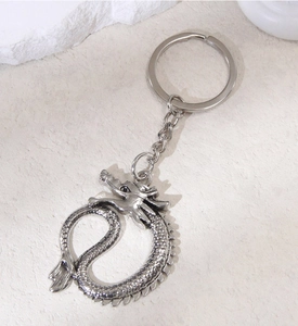 Detailed view of an antique silver metal keychain featuring a coiled dragon pendant charm