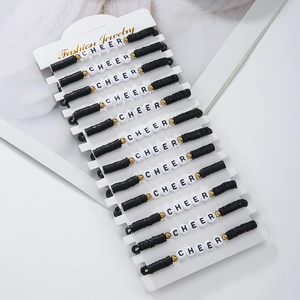 Detail of 12 black polymer clay bead bracelets with white CHEER letter beads and gold spacers